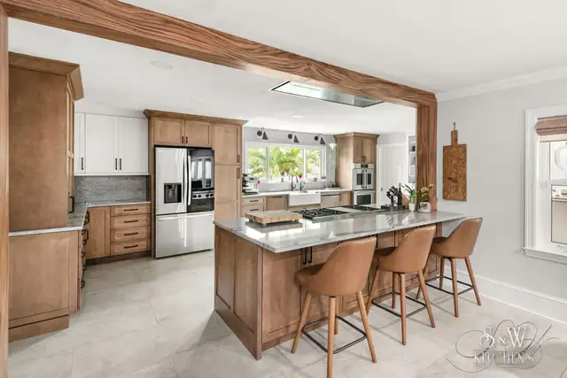 Clearwater kitchen remodel with warm wood shaker cabinets, a quartz island with seating and a wood-wrapped ceiling beam