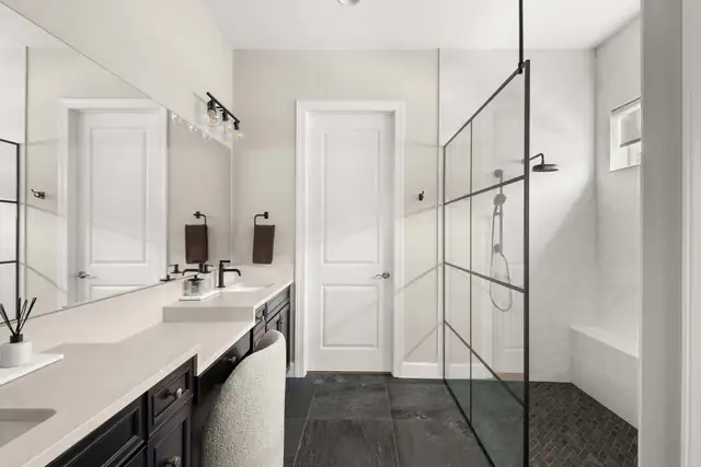 Aging-in-place bathroom with a zero-entry shower behind a black grid glass panel and a long vanity with a seated makeup area