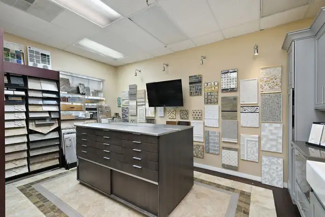 S&W Kitchens showroom with a dark cabinet display island and walls of tile and countertop samples