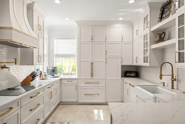 Traditional white kitchen with custom cabinets, brass hardware, farmhouse sink and an arched range hood